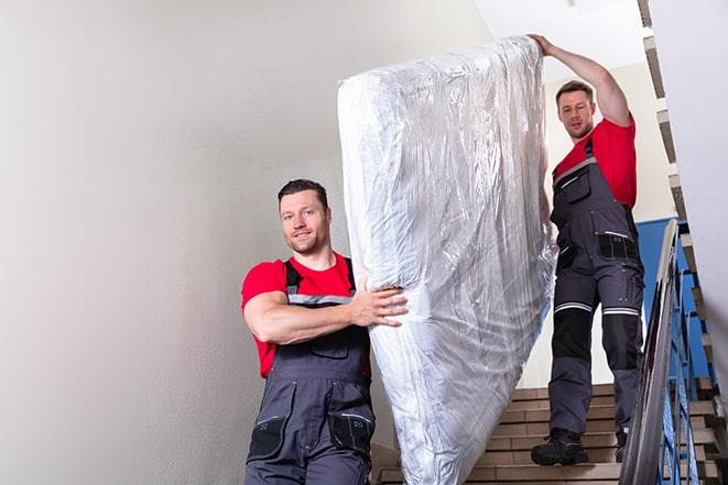 team of workers maneuvering a box spring through a doorway in Montgomery Village, MD